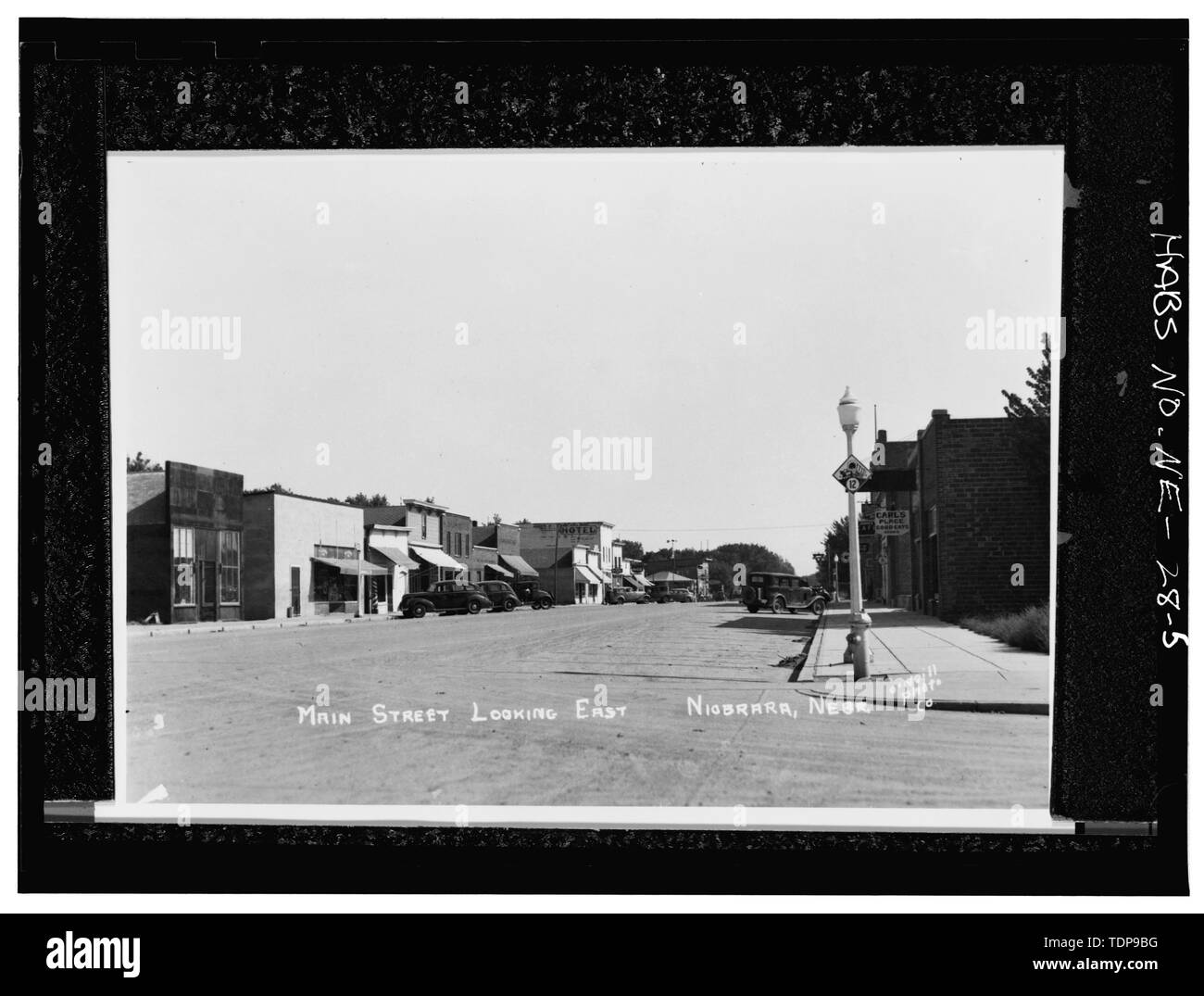 Fotocopia de bloque de ladrillo de Koster's Theatre y H. E. Bonesteel Co. store el lado izquierdo de la calle, con coches bloqueando la entrada frontal, 1930. Foto original en la Sociedad Histórica del Estado de Nebraska. - Koster's Theatre, el lado norte de Elm Street, Niobrara, Knox County, NE Foto de stock