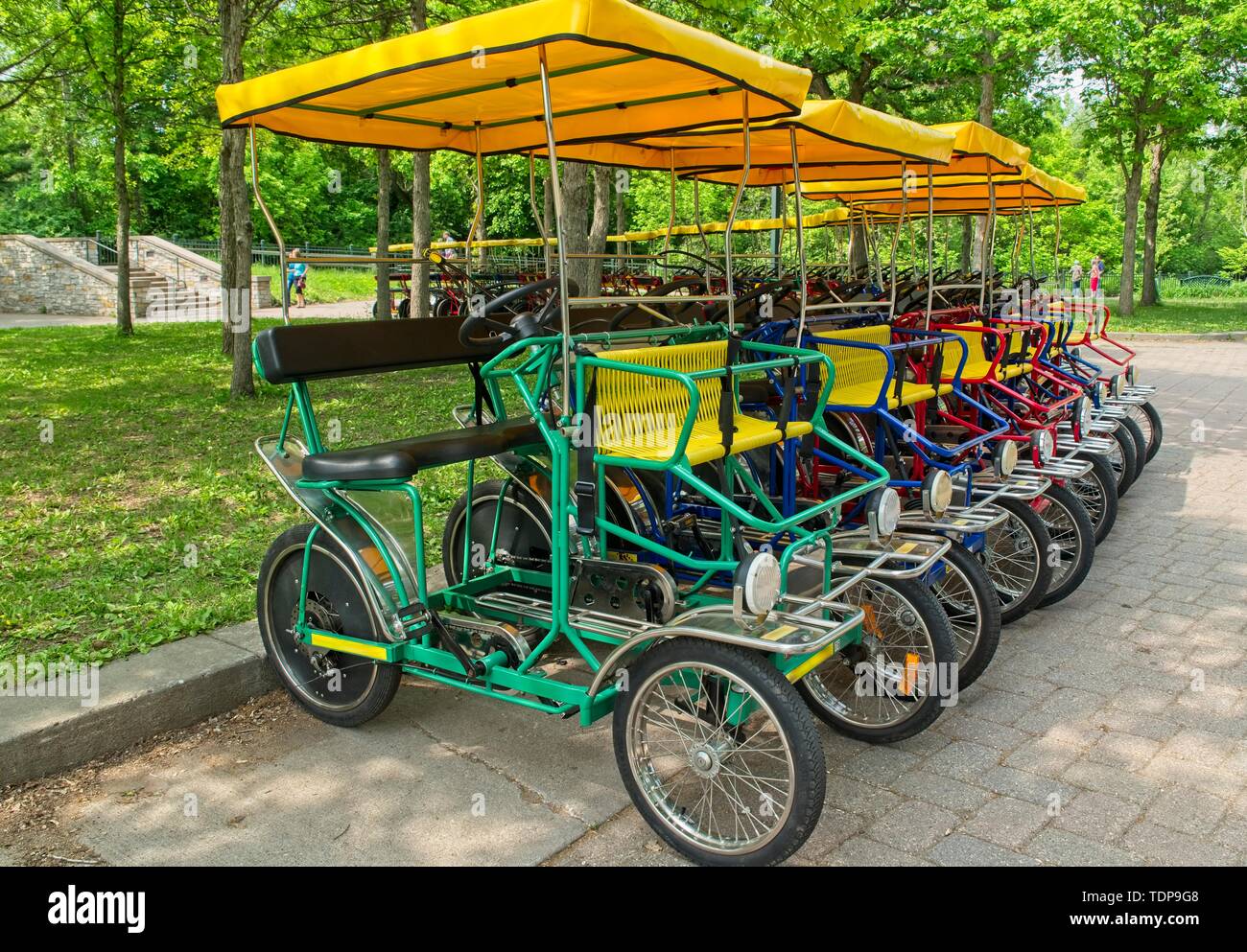 Alquiler de bicicletas de cuatro ruedas alineadas por placer en bicicleta  alrededor del parque Fotografía de stock - Alamy