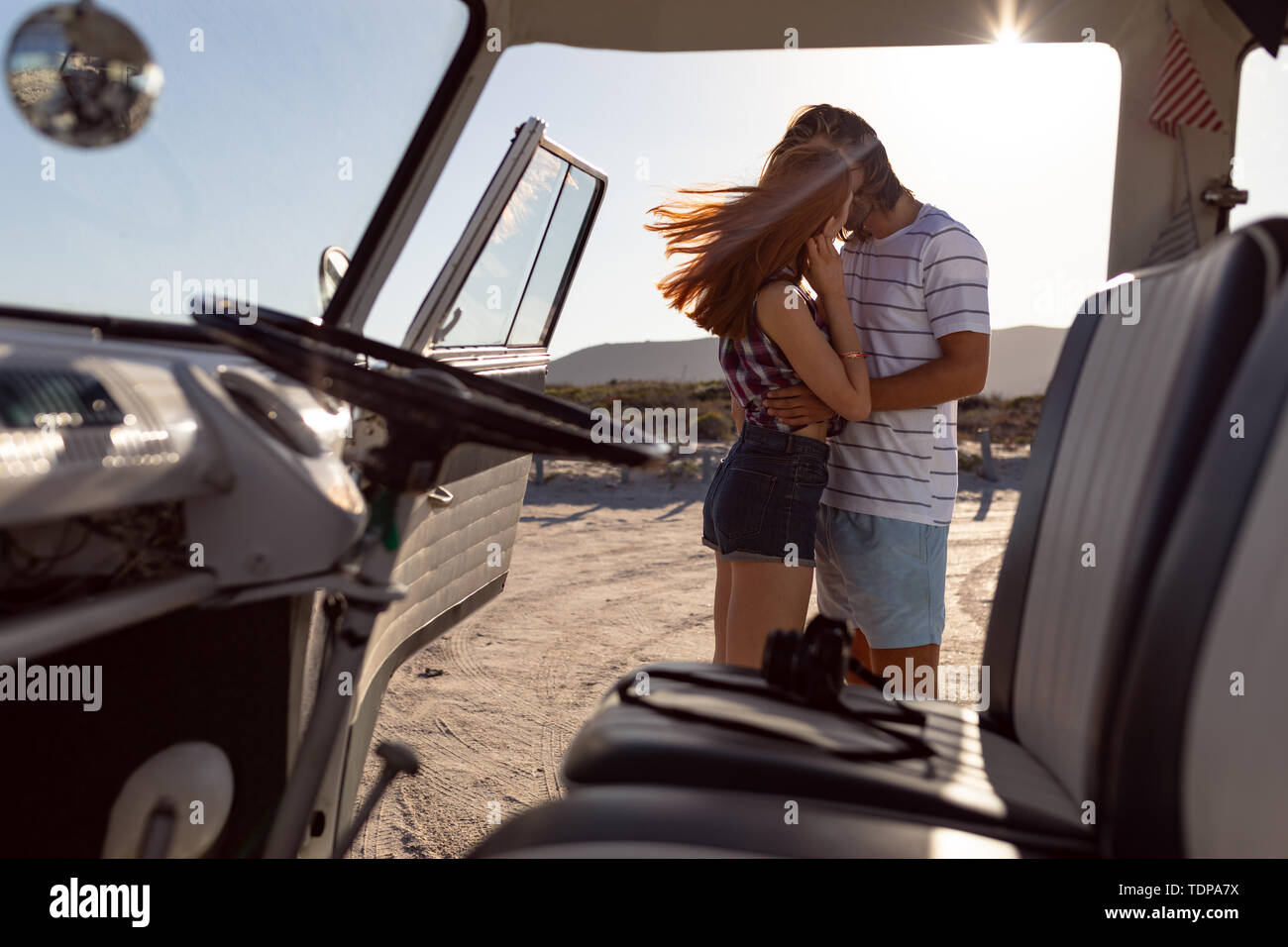 Joven pareja besándose mutuamente cerca de autocaravana en Beach Foto de stock