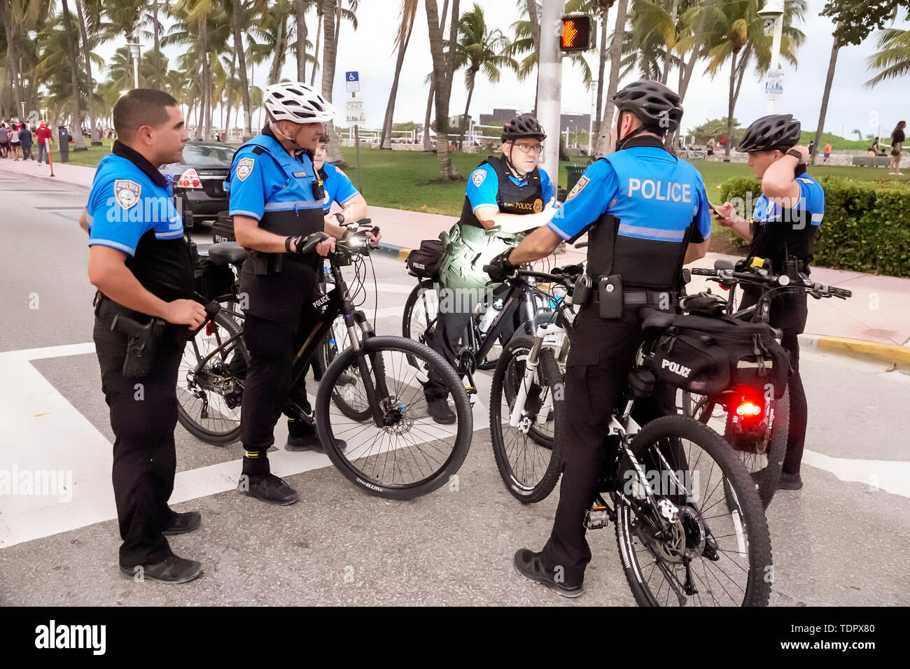 Miami Beach Florida, Ocean Drive, policía patrulla de bicicletas, huddle, hombre hombres, oficial, seguridad pública, uniforme, obtener órdenes, planificación de estrategias, FL190104036 Foto de stock