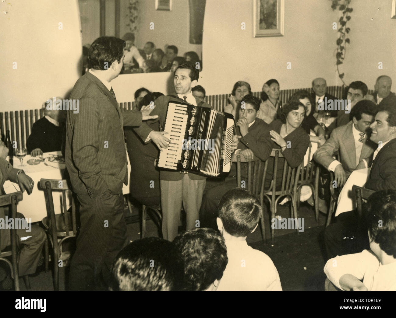 Músico juega con el acordeón en el restaurante, Italia 1950 Foto de stock