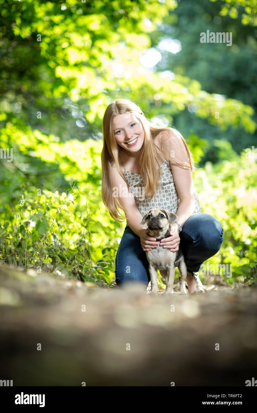 Perro doméstico (Canis lupus familiaris) f., buena apariencia joven con un Puggle, rodillazos en el terreno forestal, Alemania Foto de stock