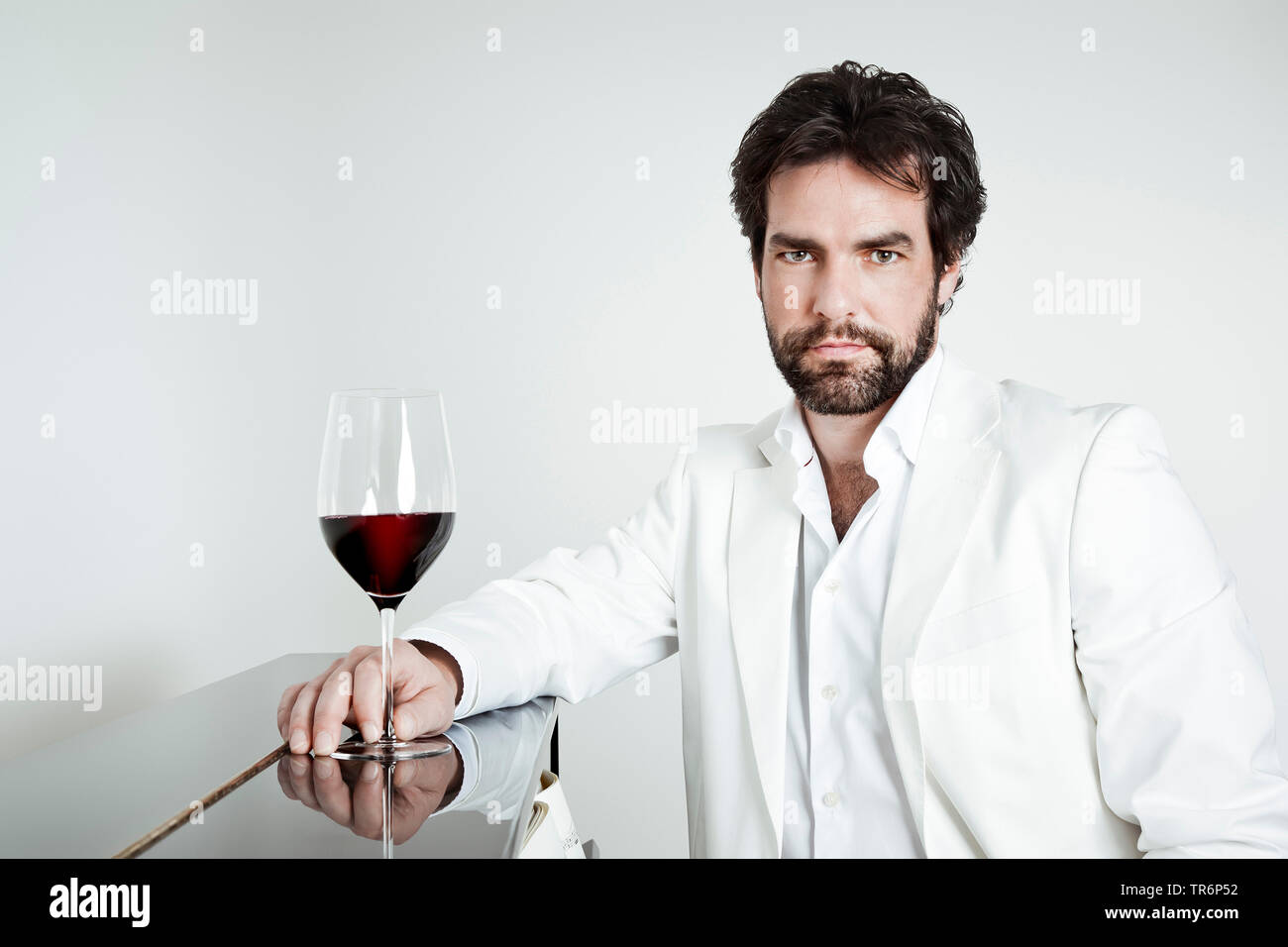 Hombre en ropa blanca con un vaso de vino tinto en la mano en el piano,  Alemania Fotografía de stock - Alamy