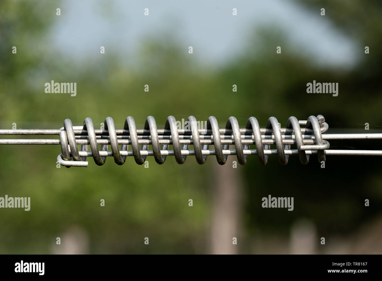Tensor de cable en espiral para cerco eléctrico exterior con fondo bokeh  Fotografía de stock - Alamy