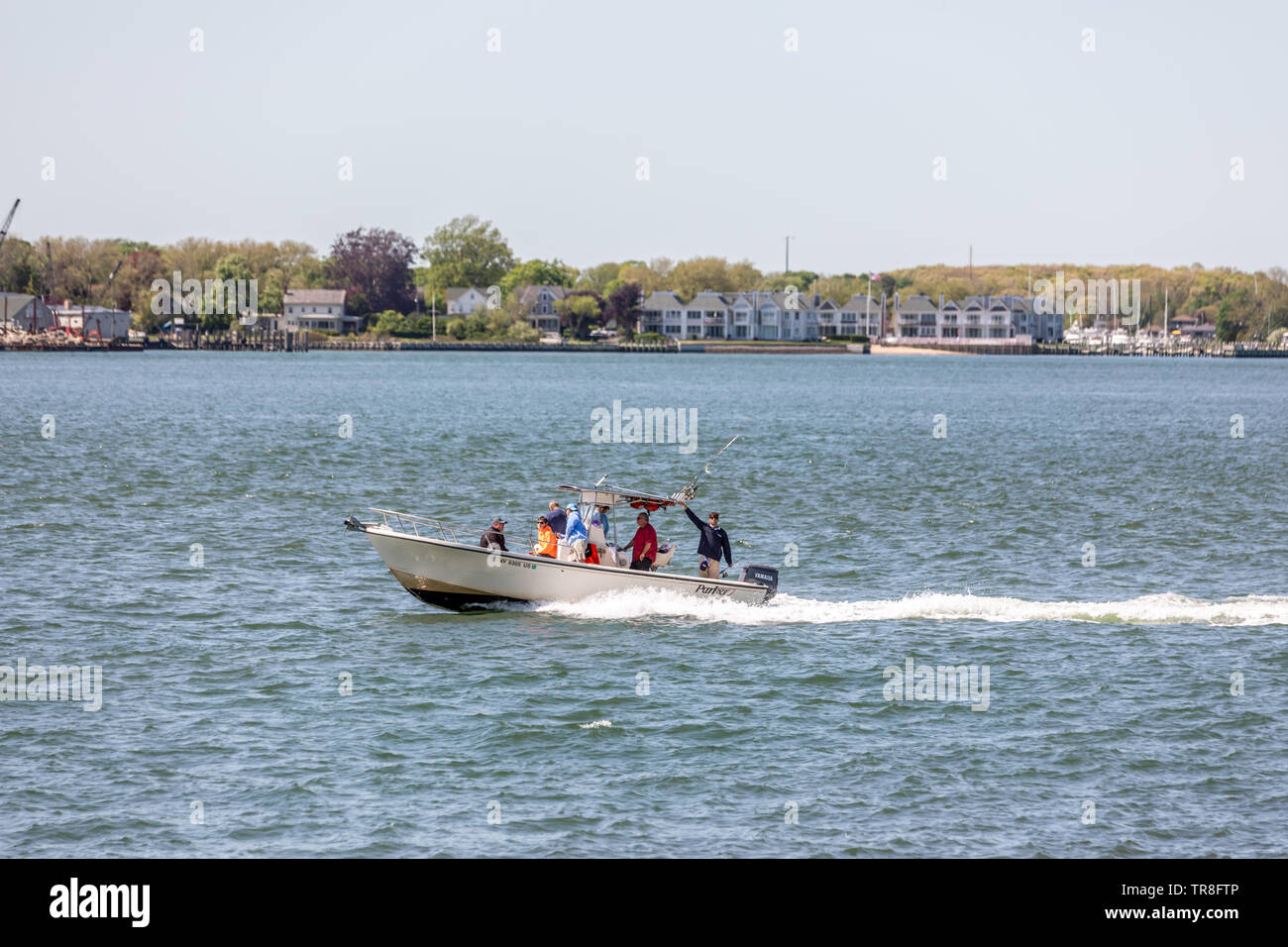 Grupo de personas en una pequeña embarcación frente a la costa de Greenport, NY Foto de stock