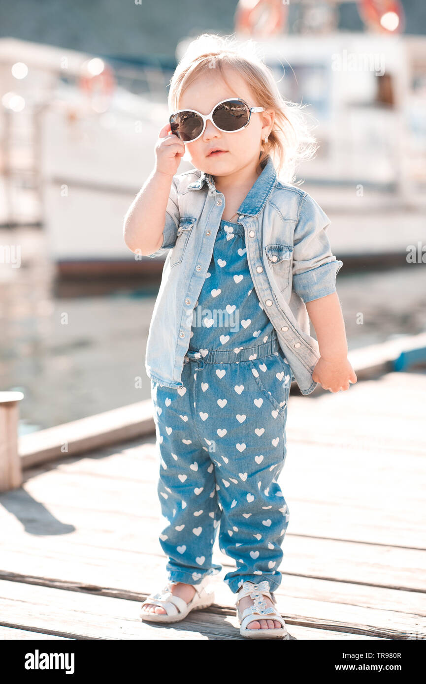 Elegante niña 2-3 años vistiendo ropa denim afuera. Mirando a la