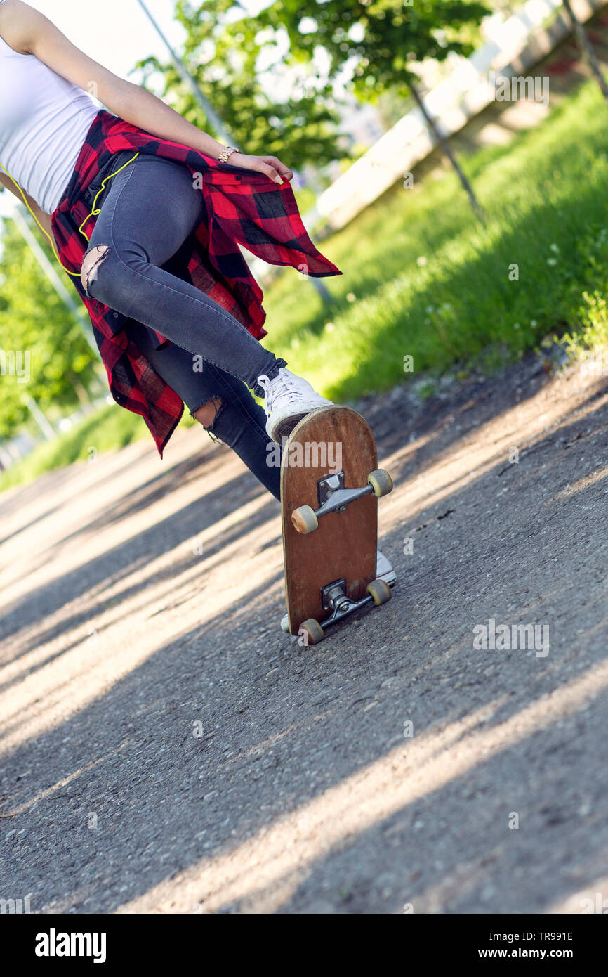 Chica skater - piernas skateboarding en estacionamiento Foto de stock