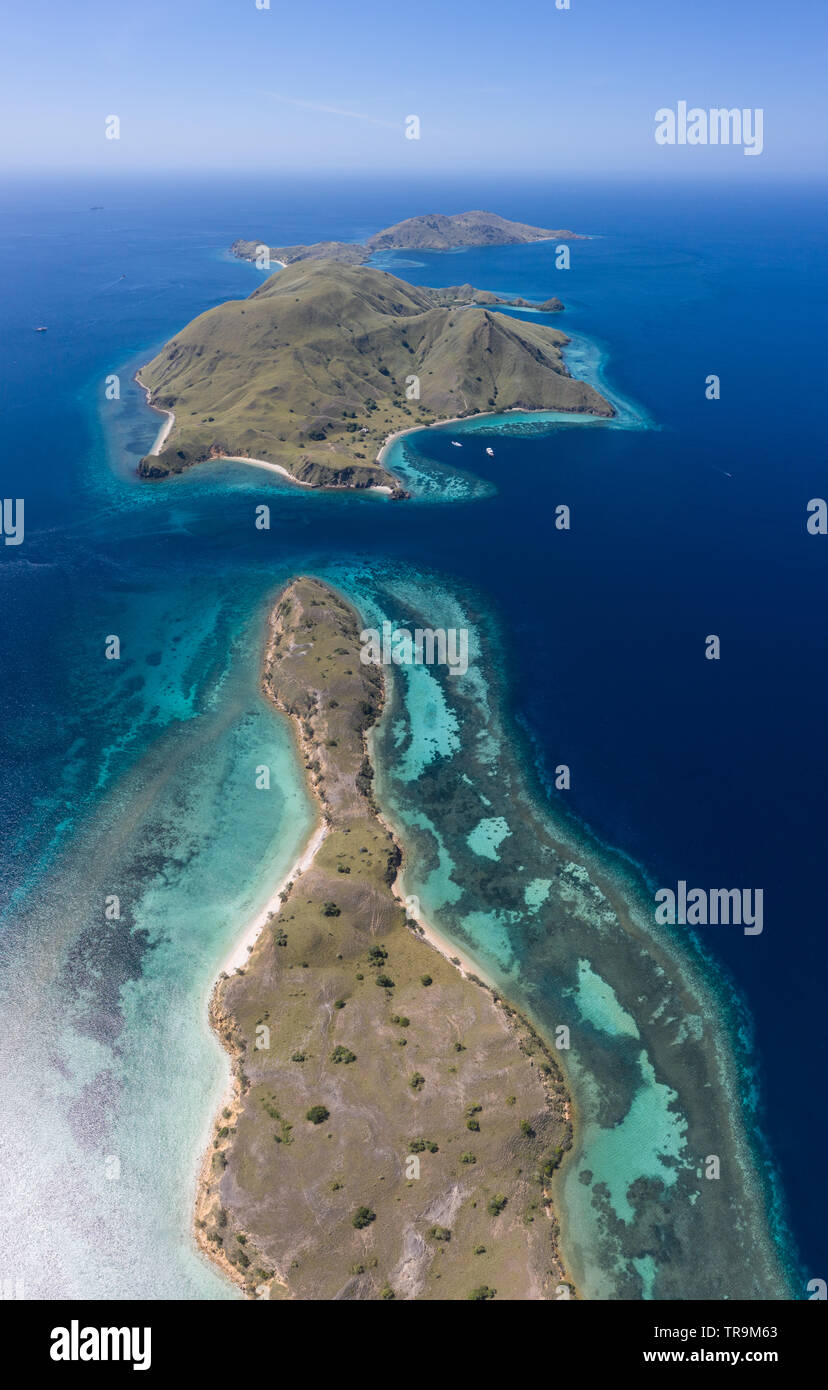 Visto desde una vista de pájaro, las islas tropicales en el Parque Nacional de Komodo, en Indonesia, están bordeadas por increíbles, biodiversidad de los arrecifes de coral. Foto de stock