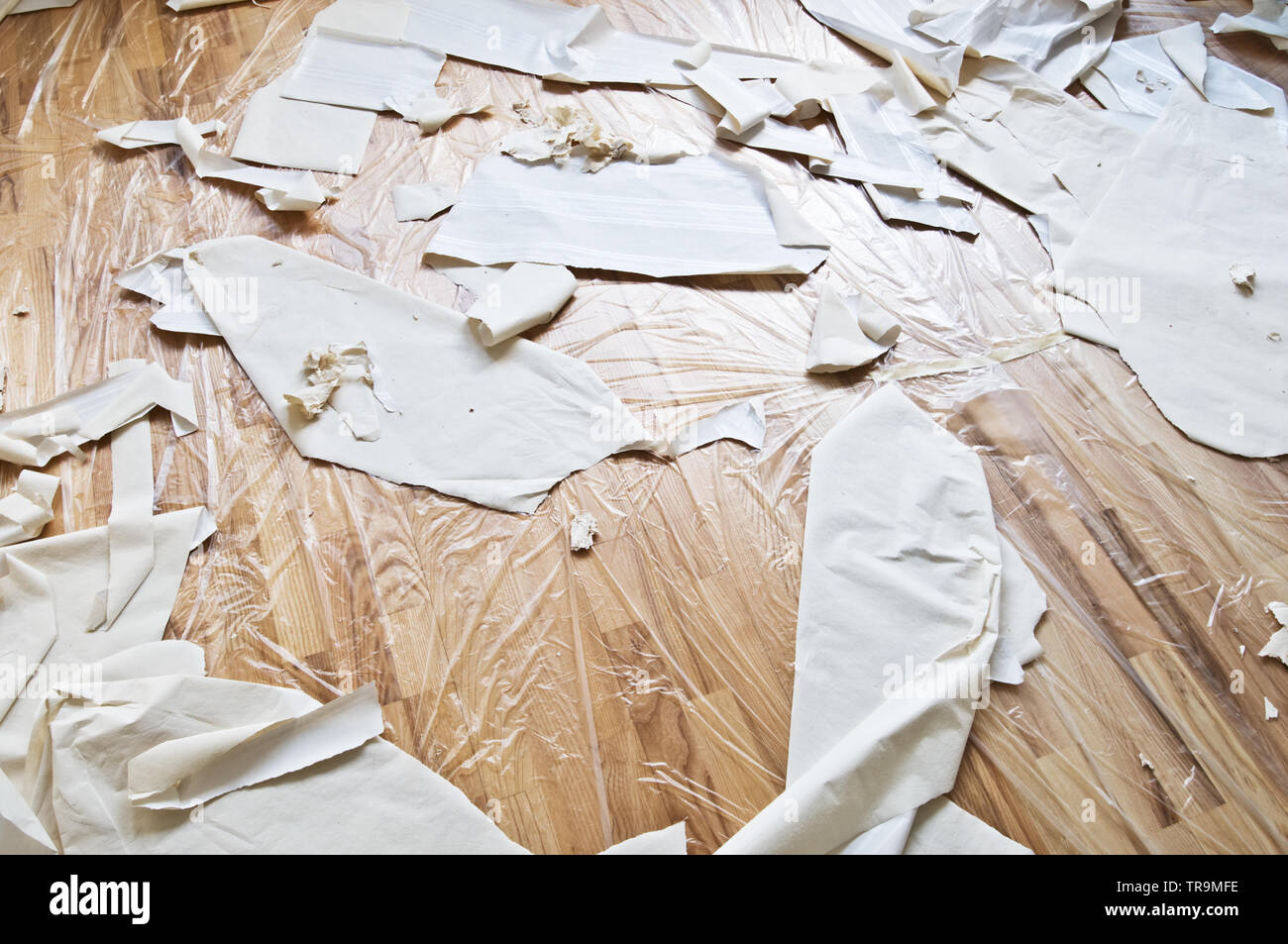 Renovación interior. Suelo de parquet bajo la protección de plástico, papel y retazos de papel tapiz. Foto de stock