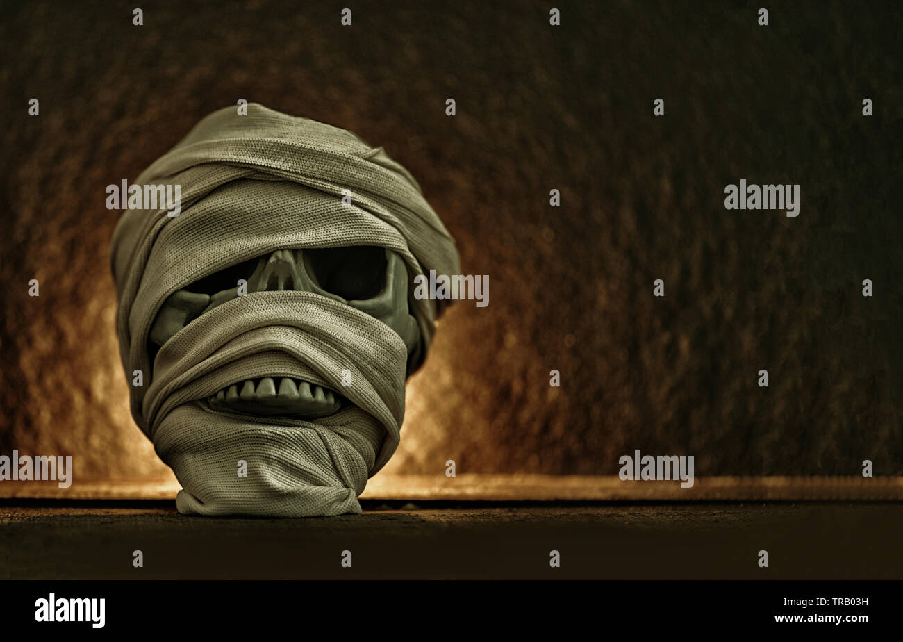 Momia cubiertas por la ropa en cráneo decorado en halloween cosplay y luz sobre fondo oscuro Foto de stock