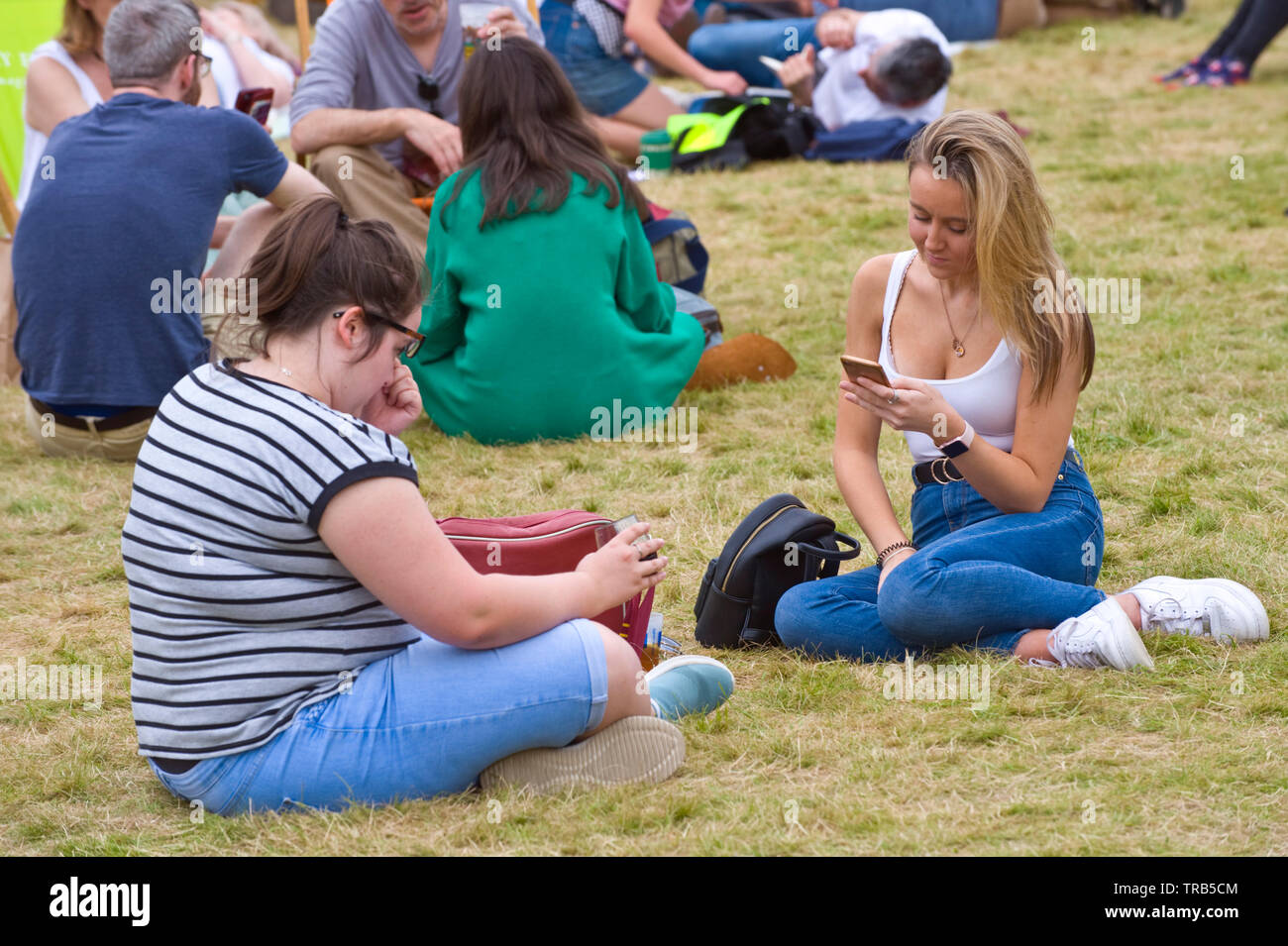 Las mujeres jóvenes relajándose en el césped en el Festival del heno heno en Wye Gales Powys UK Foto de stock