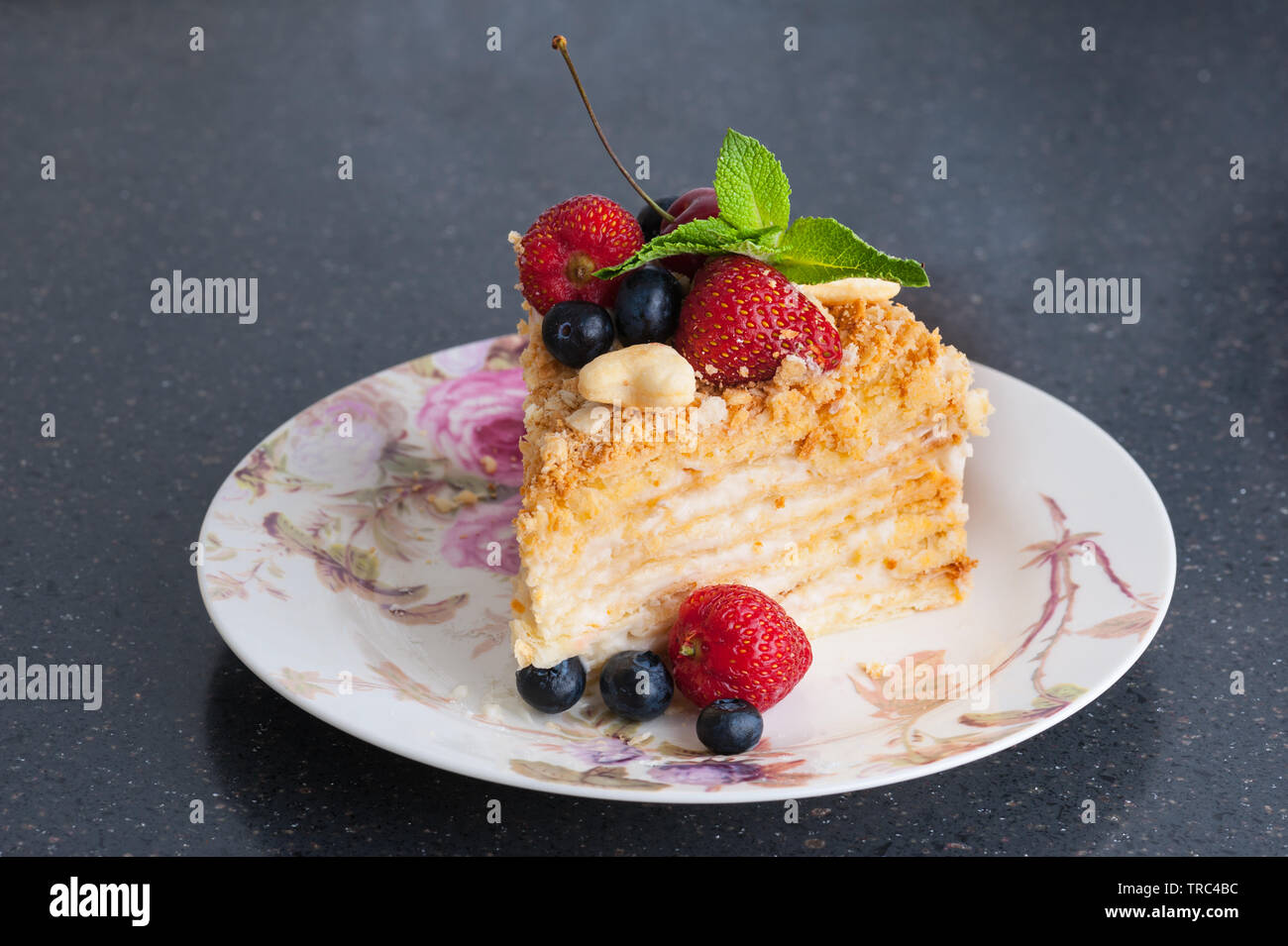 Un trozo de tarta napoleón en placa con bayas Foto de stock