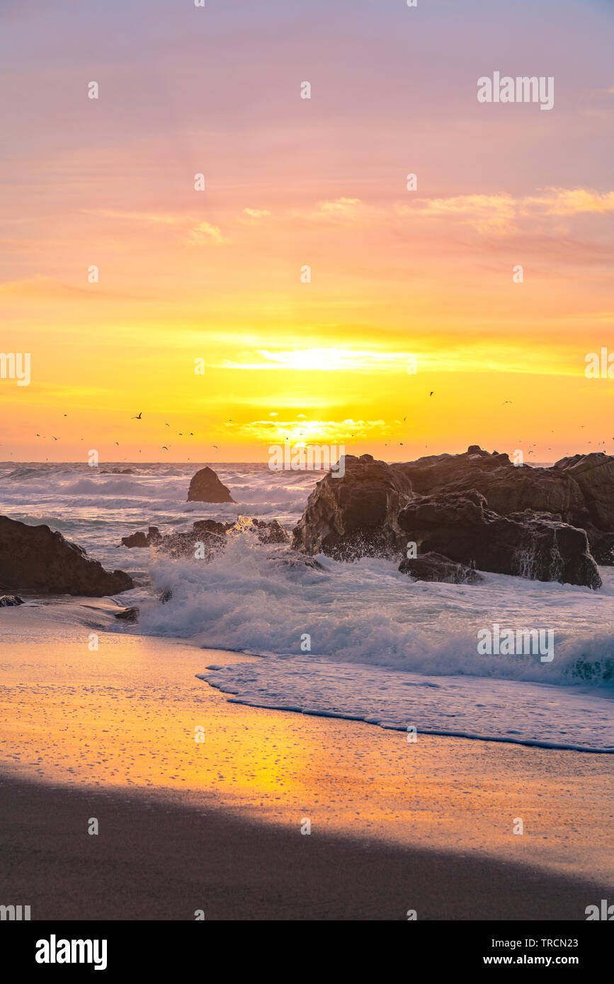 Las olas en la orilla móviles como las puestas de sol en el horizonte a lo largo de la famosa carretera uno cerca de Big Sur, California Foto de stock