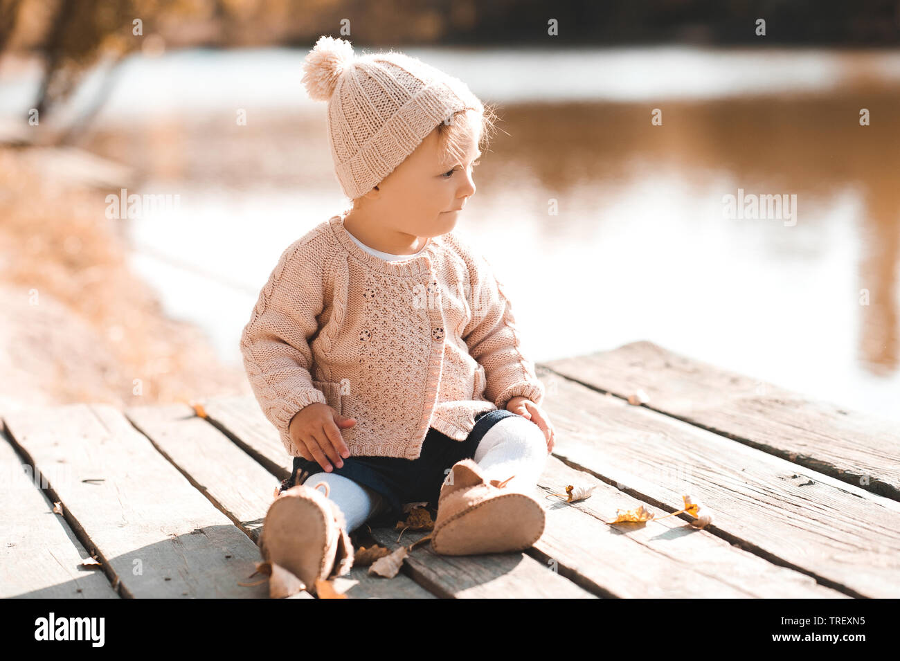 Niña sonriente de 1 a 2 años con ropa elegante de punto sentada al aire  libre