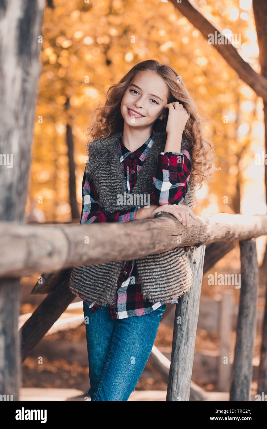 Hermosa niña rubia de 12-13 años en ropa informal posando en la calle.  Concepto de estilo de vida infantil. Crear espacio de copia. Mantenga  pulsado el botón azul s Fotografía de stock 