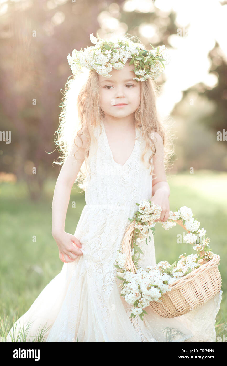 Lindo bebé niña 3-4 años a la moda vestido blanco y ofrenda floral al aire libre. Sosteniendo la cesta flores. La infancia. Día de boda Fotografía de stock - Alamy