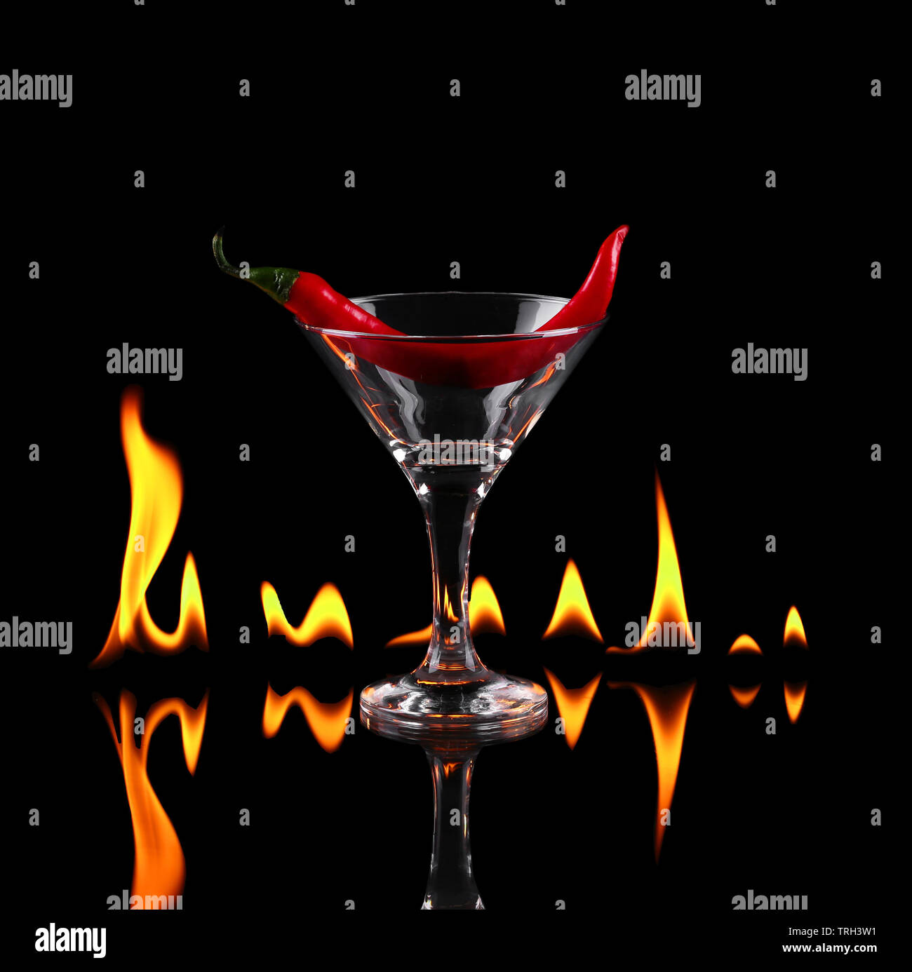 Hot Chili Pepper en una copa de martini con un fuego sobre un fondo negro Fotografía de stock