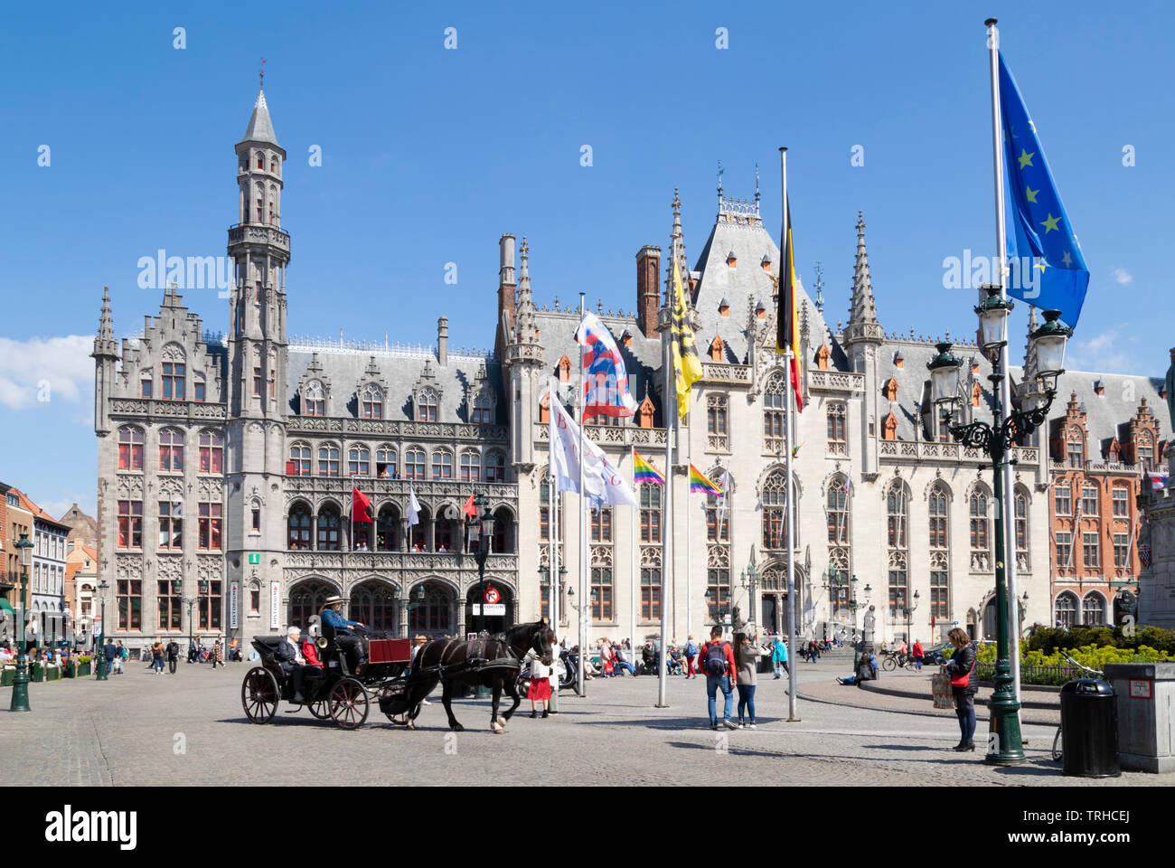Los turistas visitar Brujas en un carruaje tirado por caballos pasando por el Tribunal Provincial Provinciaal Hof en el Markt de Brujas Bélgica UE Europa central Foto de stock