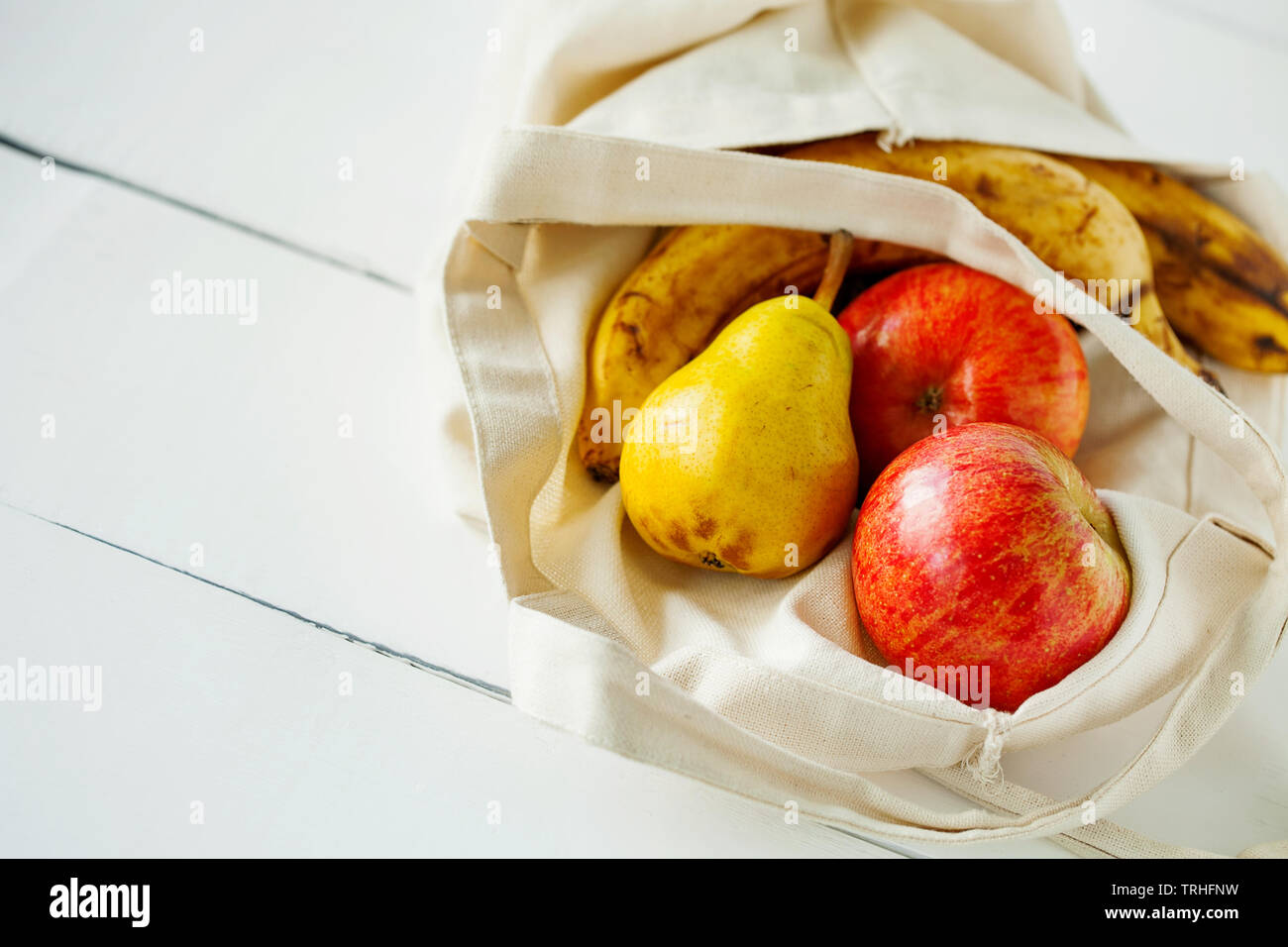 Frutas frescas orgánicas en tejido de algodón ecológico y producir paquetes de bolsas en la mesa de cocina de madera blanca ver copia de espacio.Cero residuos Foto de stock