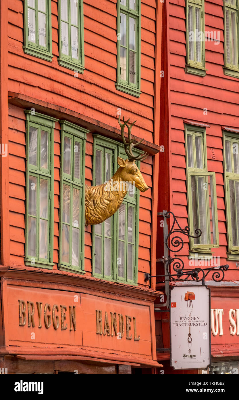 Coloridas de madera figura de un ciervo de oro Golden ciervo en la pared de una casa de madera en el histórico barrio Hanseática en Bryggen, Torget, el alemán WHA Foto de stock