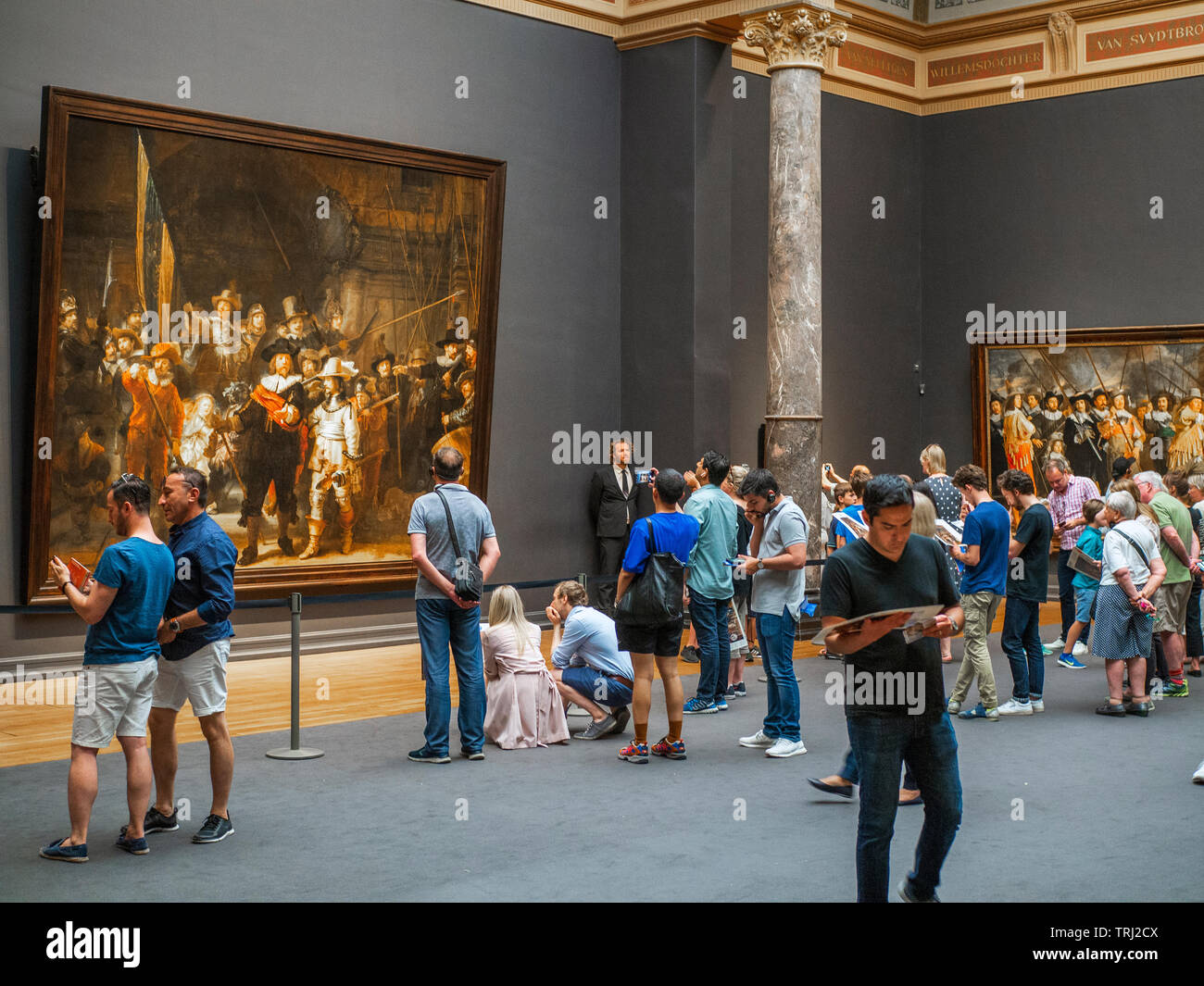 Turista mirando los The Night Watch, una pintura de Rembrandt Harmenszoon van Rijn, en el Rijksmuseum de Amsterdam, Países Bajos. Rembrandt es consi Foto de stock