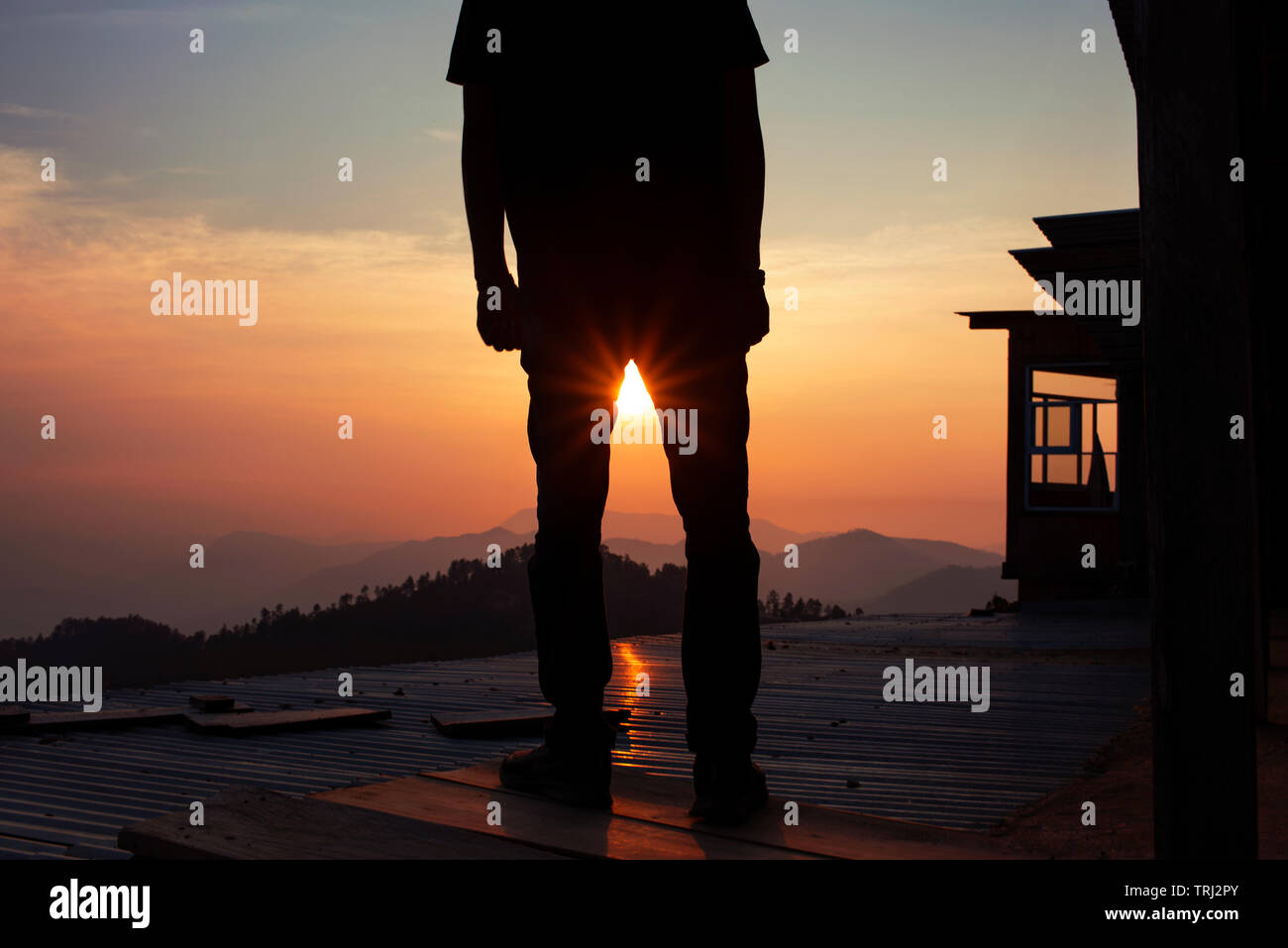 Silueta de un hombre de pie sobre el techo alto viendo la puesta de sol. San José del Pacifico, Oaxaca, México. Mayo de 2019 Foto de stock