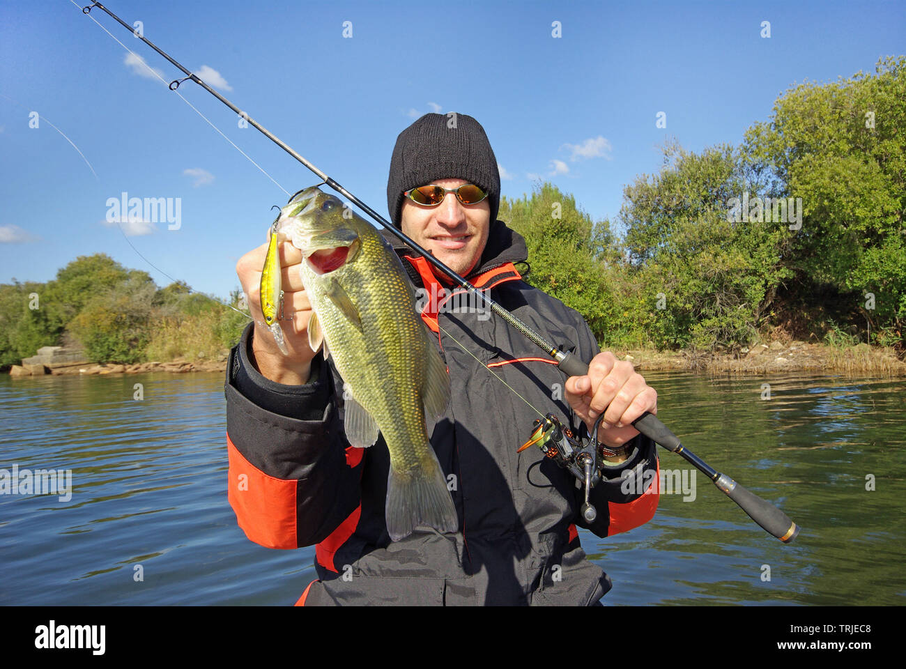 Lucky fisherman sosteniendo un larg bass pescado. La pesca de agua dulce, la pesca con cebo, pesca embarcada Foto de stock