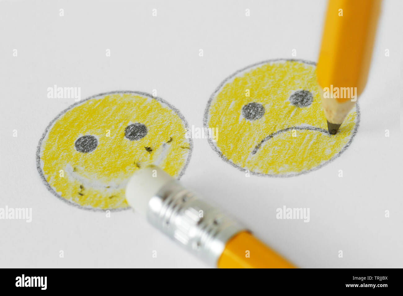 Dibujo de una cara sonriente con expresiones negativas y positivas con lápiz y goma - emoción negativa concepto Foto de stock