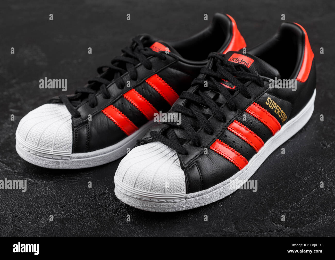 Londres, Reino Unido - Junio 05, 2019: Originales Adidas Superstar zapatos  negros con franjas rojas sobre un fondo negro Fotografía de stock - Alamy