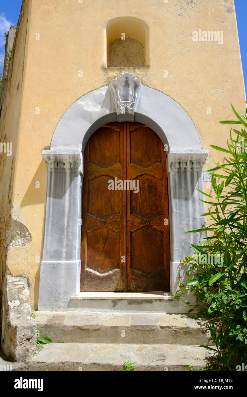 Casa italiana tradicional y colorida con umbral arqueado y puerta de madera en Positano en la Costa Amalfitana de Campania, en el sur de Italia Foto de stock