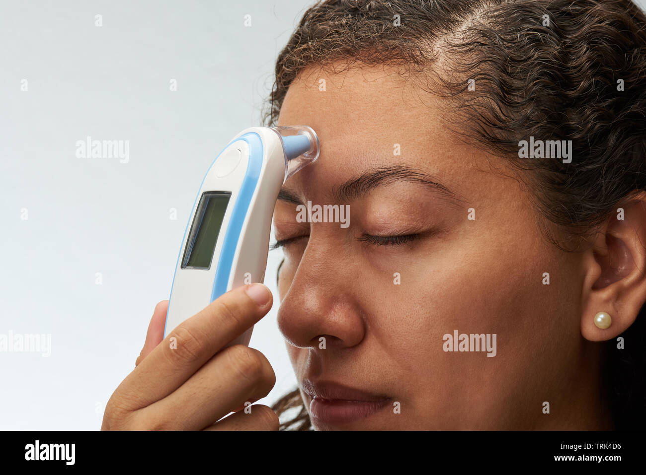 Control de la temperatura corporal el tema. Mujer joven con termómetro digital junto al frente Foto de stock