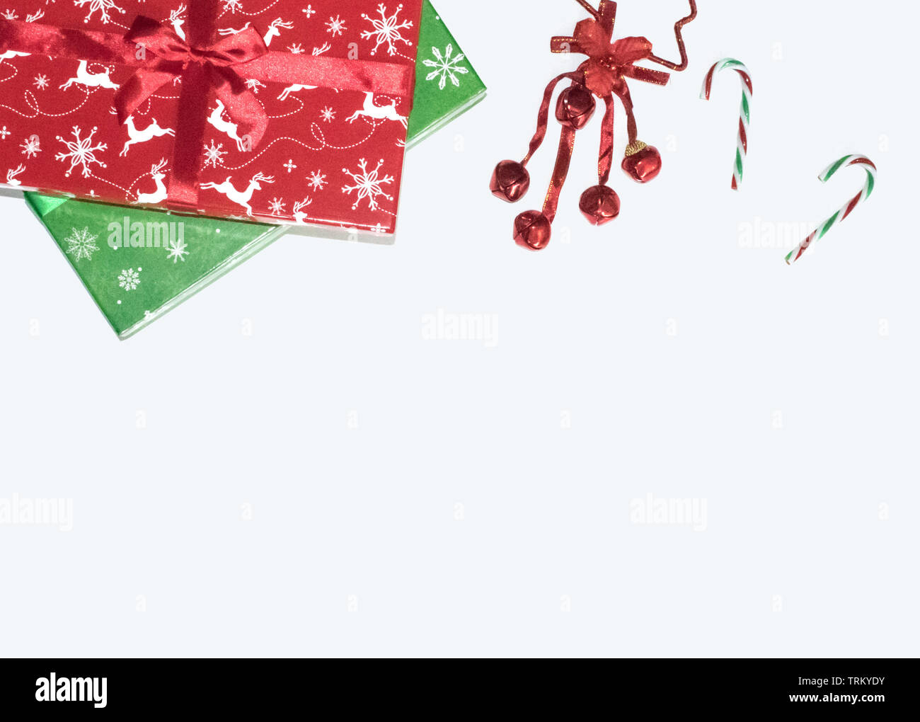 Caja de regalo de Navidad se presenta con decoraciones sobre fondo blanco, laicos plana vista superior, adornos de Navidad, rojo, verde y bastones de caramelo y campanas composición Foto de stock