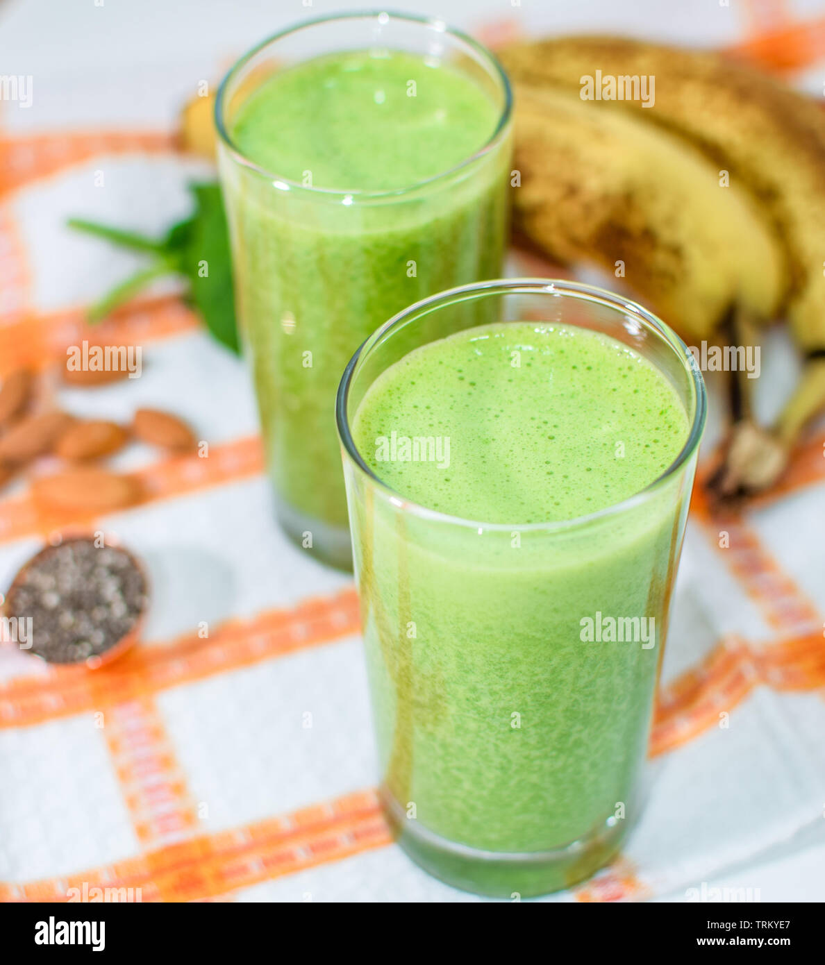 Espinacas y plátano verde smoothie saludable con almendras y semillas de chia en un vaso Foto de stock