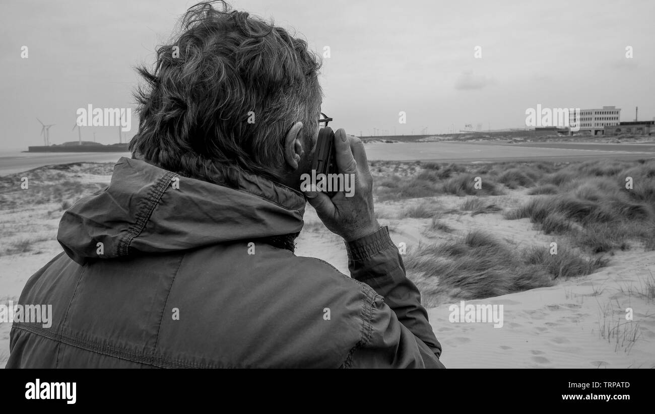 El hombre manejar un teléfono móvil mientras camina en las dunas de arena, de Boulogne-sur-Mer, Hauts de Francia, Francia Foto de stock