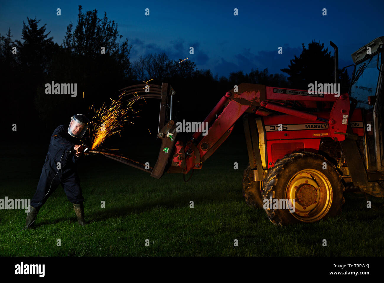 Un agricultor haciendo reparaciones hasta tarde en la noche Foto de stock