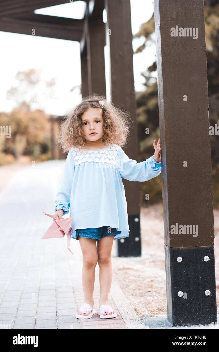 Elegante niña 3-4 años vistiendo ropa de moda de verano la celebración de  juguete al aire libre. Mirando a la cámara Fotografía de stock - Alamy