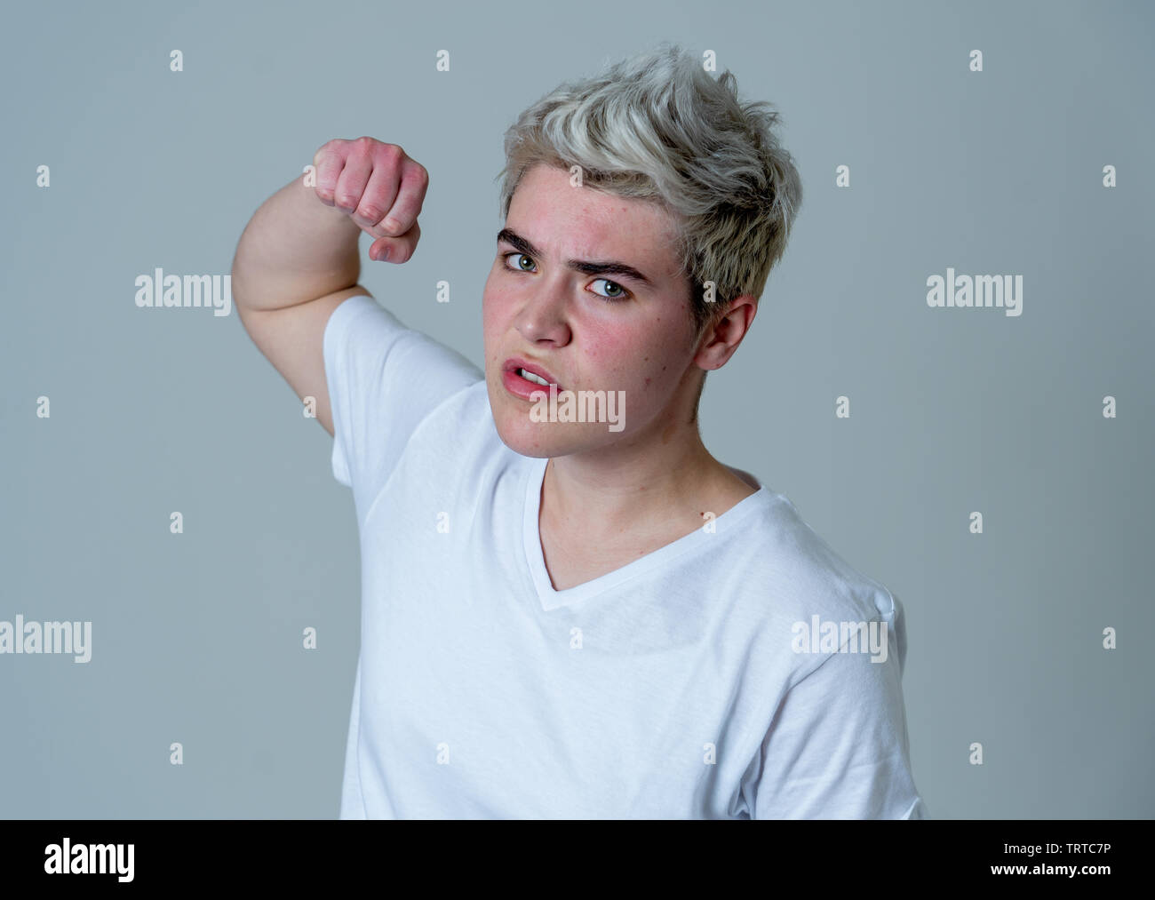 Retrato de joven adolescente transgénero atractivo hombre con enojo. Mirando enojado y furioso. Las expresiones faciales y emociones. Aislado en punto muerto b Foto de stock