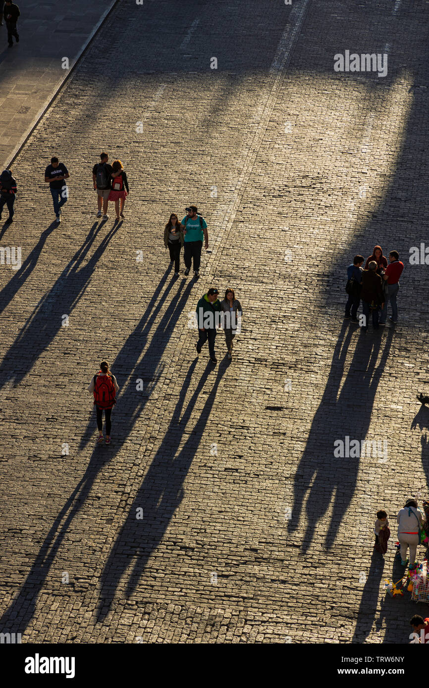 Los peatones arrojar sombras largas en la Plaza de Armas de adoquines a última hora de la tarde en Arequipa, Perú, América del Sur Foto de stock