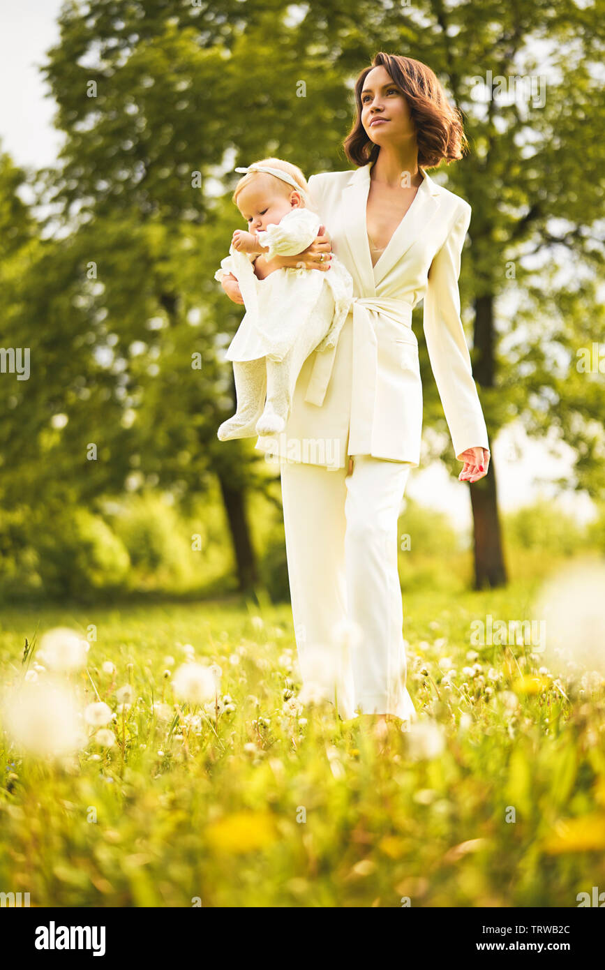Outdoor retrato de moda joven hermosa madre e hija poco lindo en un prado con el diente de león. Imagen de primavera Foto de stock