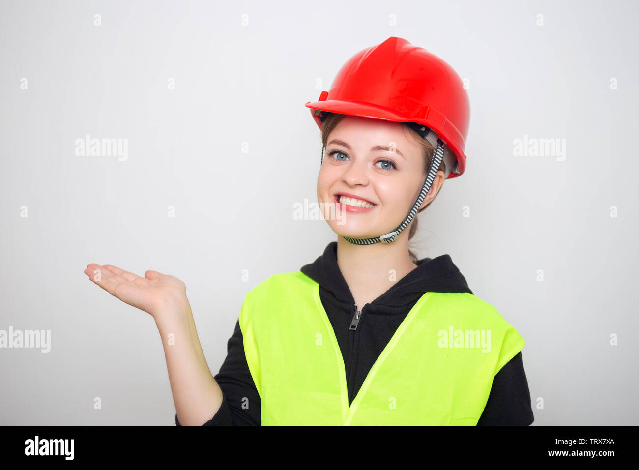 Joven mujer caucásica vestidos de rojo casco de seguridad y chaleco reflectante, sonriendo Foto de stock