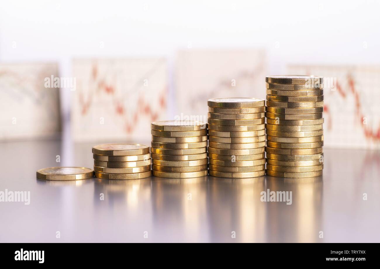 Aumento de los montones de monedas y gráficos con los precios de las acciones en el fondo mundial de uso | Foto de stock