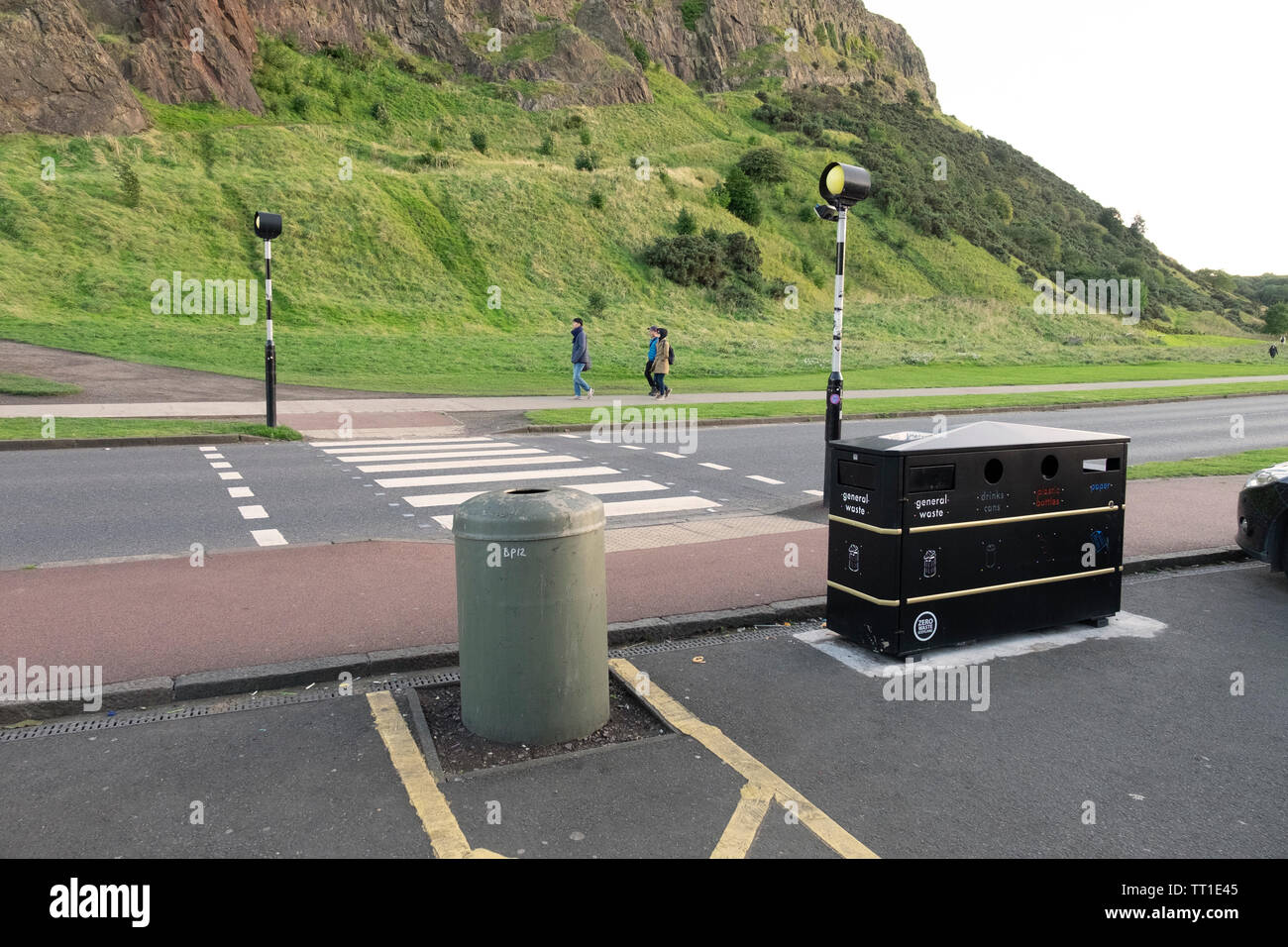 Mobiliario Urbano - paso de cebra, bin y papelera de reciclaje y el pueblo por la carretera en Holyrood Park, Edimburgo, Escocia Foto de stock