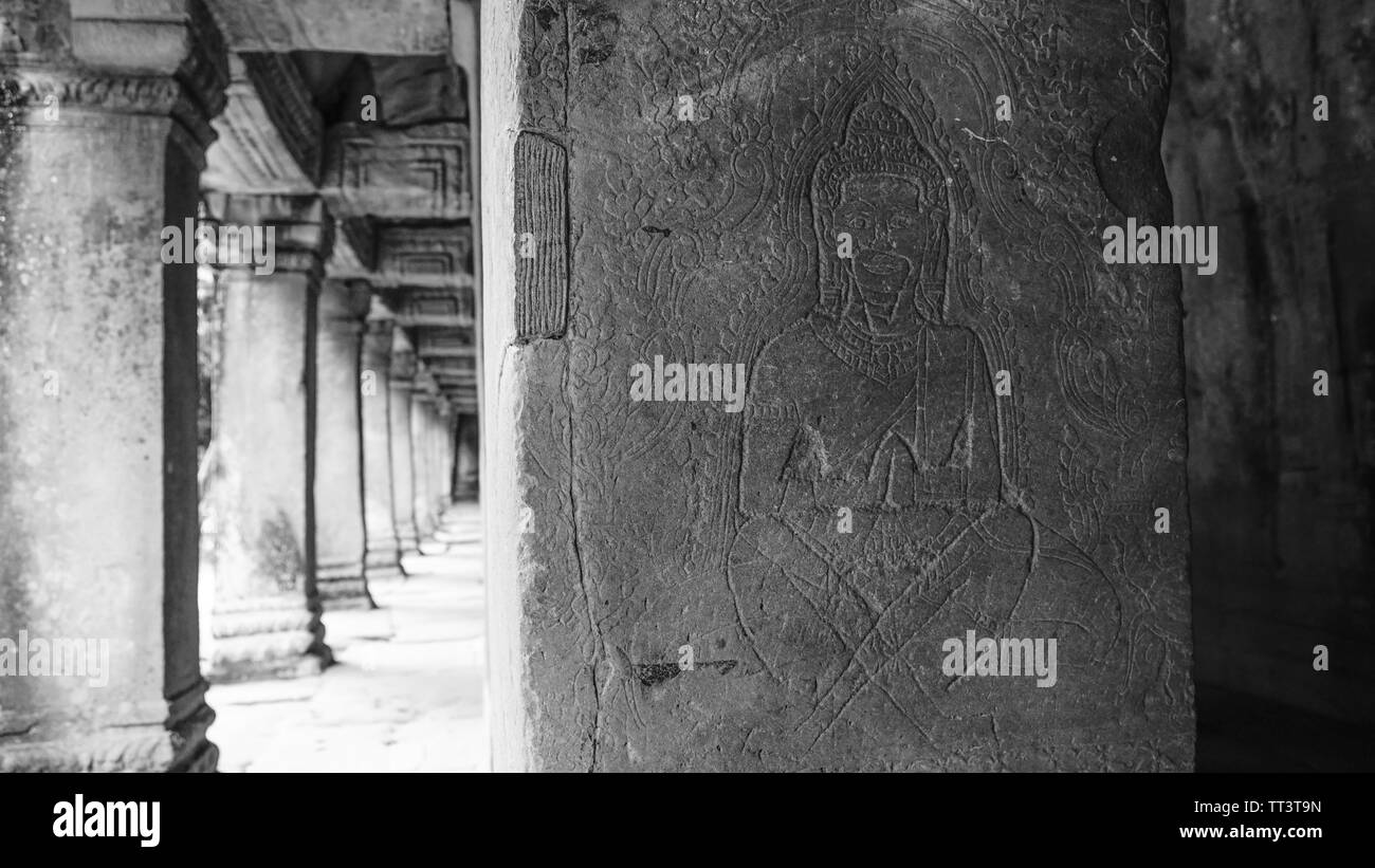 Detalle de la escultura antigua con un corredor borrosa en el fondo en perspectiva decreciente en el hermoso templo Bayon - un decorado Khmer Foto de stock