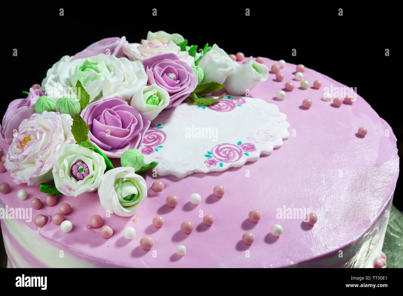 Tarta de galletas en capas con crema de mascarpone y crema de bayas y flores de masilla en la oscuridad Foto de stock