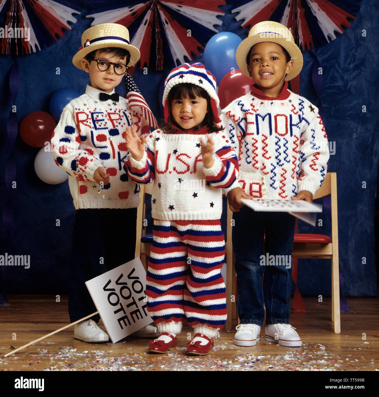 Tres niños vestidos con ropa tejida para sacar el voto Foto de stock