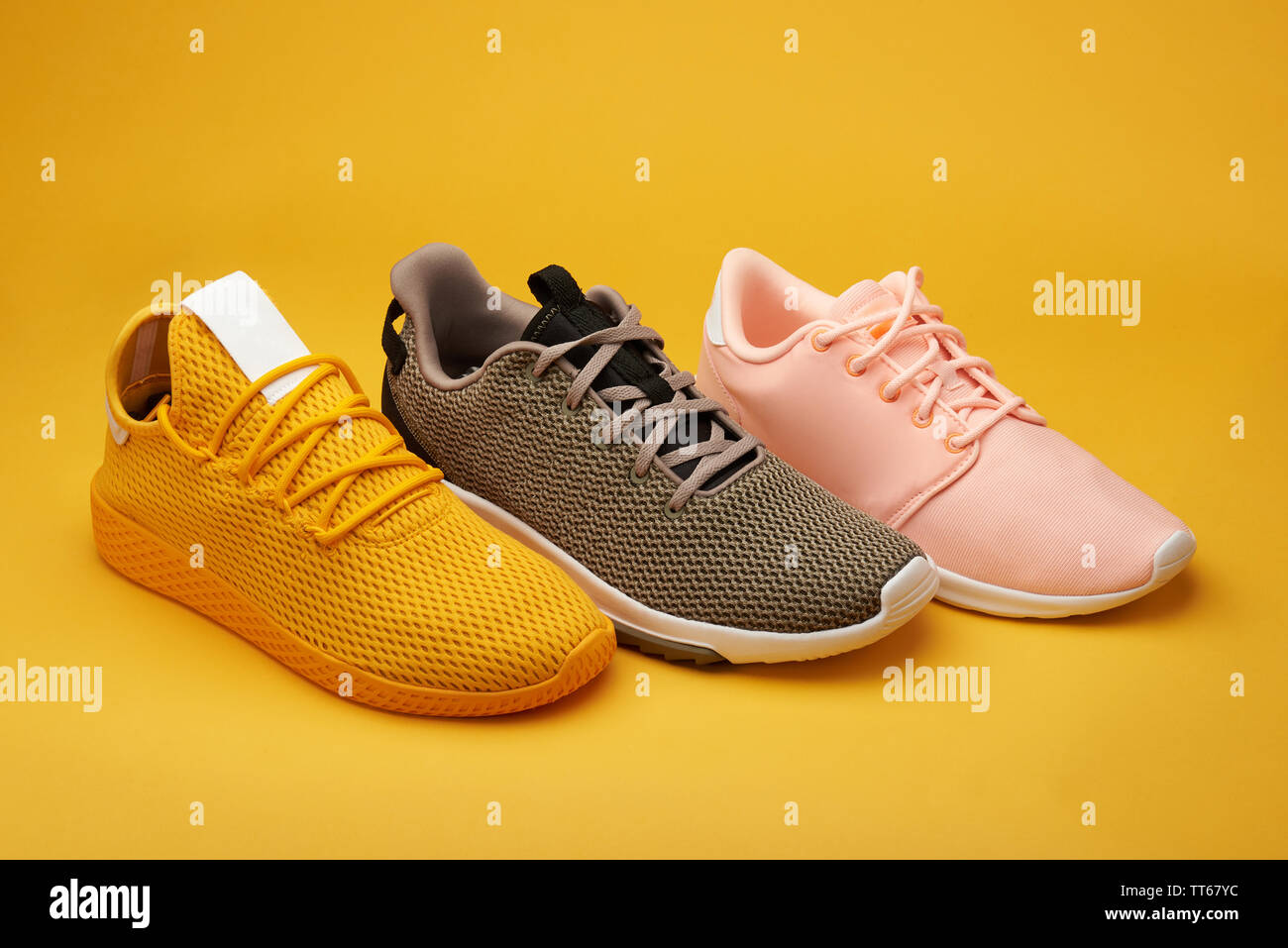 Grupo de coloridos zapatos deportivos pararse sobre fondo naranja Foto de stock
