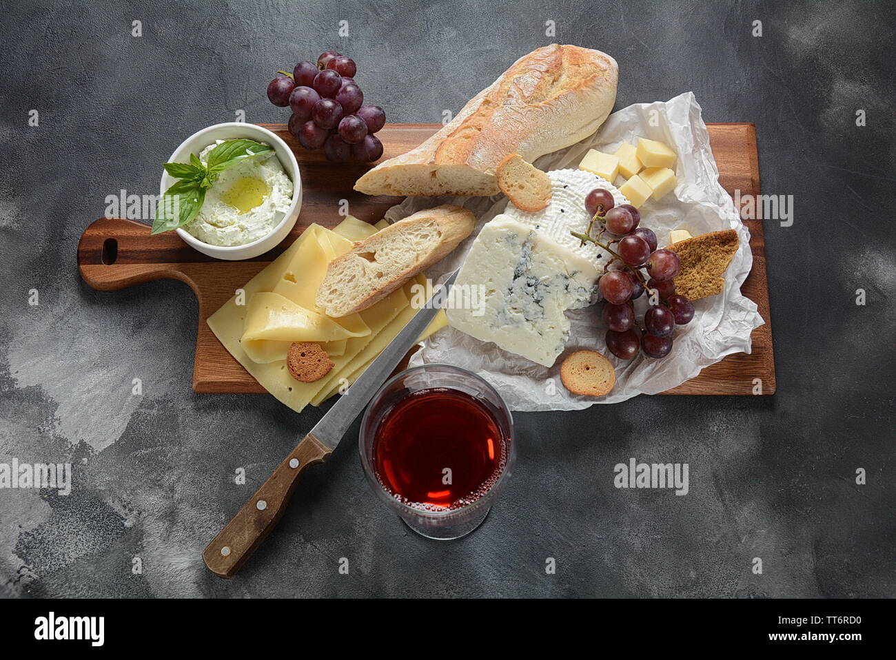 Tabla de quesos con un surtido de quesos, uvas, bocadillos sobre fondo