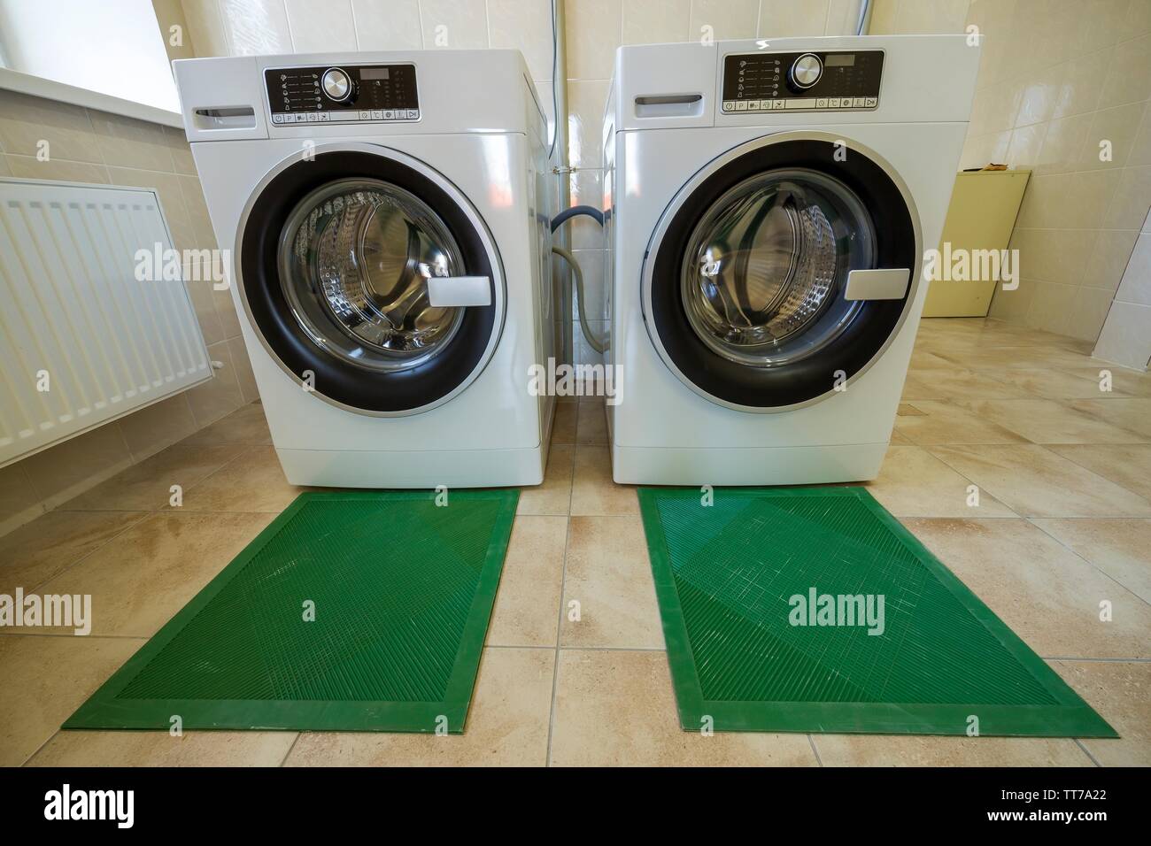 Nuevas modernas máquinas lavadoras industriales en baldosas en el cuarto de baño o de lavandería en aislamiento de goma alfombrillas Fotografía de stock - Alamy