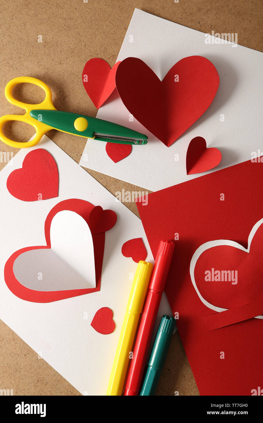 Hermoso post hechas a mano tarjetas, bolígrafos y tijeras con corazones de  papel en el color de fondo de madera Fotografía de stock - Alamy