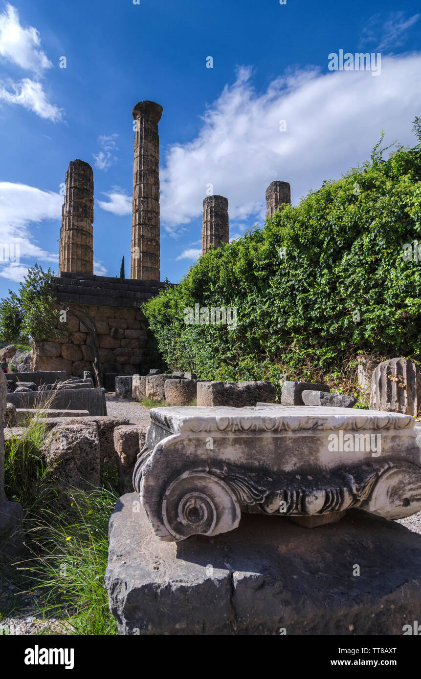 Delphi, Phocis / Grecia. Templo de Apolo y un orden jónico capital de una antigua columna en el sitio arqueológico de Delfos. Día soleado, nublado cielo Foto de stock
